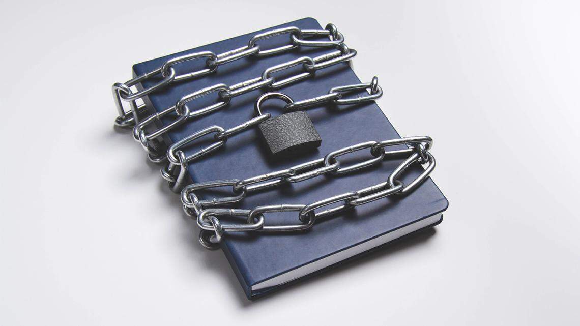 book is locked under lock and key on a white background. Secret archive. Chain on the book close-up. The book of secrets is under lock and key. secrecy sunshine law transparent transparency document file government