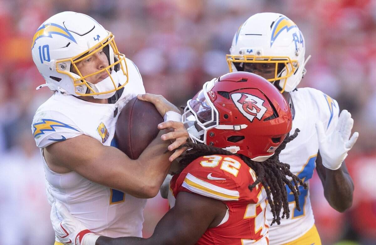Los Angeles Chargers quarterback Justin Herbert (10) is tackled by Kansas City Chiefs linebacker Nick Bolton (32) during the first half on Sunday at Arrowhead Stadium.