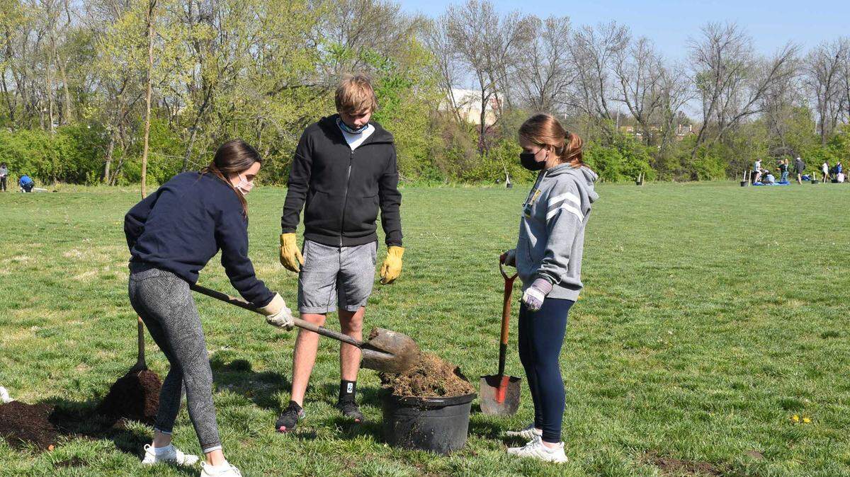 Katie McElroy, Ike McLey and Dylan Ziegler plant trees at Tomahawk Park.