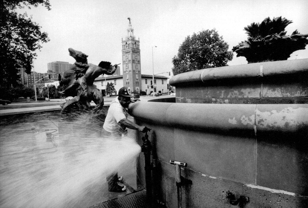 Fred McClain of the Parks and Recreation Department drains and cleans the J.C. Nichols Fountain near the Country Club Plaza in 1990. In 2020, the J.C. Nichols name was removed from the fountain and it is now referred to as the fountain in Mill Creek Park.