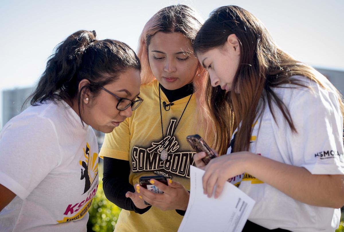 Ana Jimenez (left) and Noellia Saenz (right) looked on as Frida Sanchez, 19, (center) of The Kansas/Missouri Dream Alliance, explained an app used for canvassing on Saturday in Kansas City, Kan. The volunteers were seeking out Latinos voters to encourage voter participation. Sanchez, who, as a 5-year-old came to the United States with her parents from Mexico, is not an American citizen, so she cannot vote, but is passionate about getting Latinos to vote.