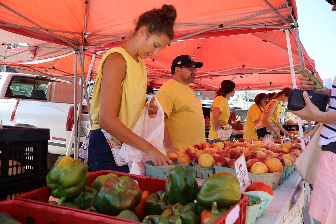 A worker for Beckner’s Orchards bags peaches for a customer on Saturday, Aug. 16, in Lee’s Summit.