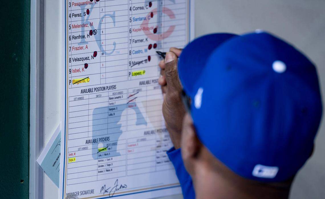 A Kansas City Royals bench coach marks a player roster on the wall of the dugout during the Royals’ home opener against the Minnesota Twins.