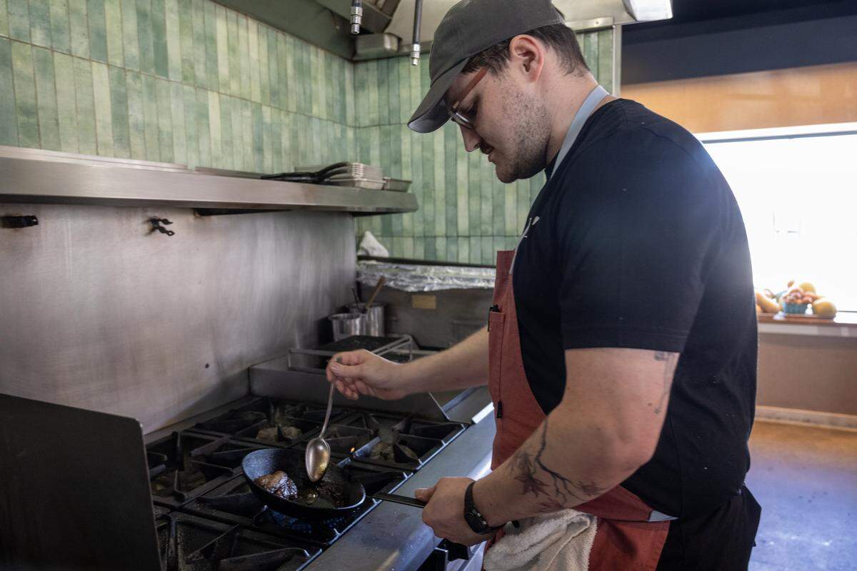 Sam Edelson, chef de cuisine, bastes a piece of Missouri catfish in house made olive oil for Chawanmushi, a dish featuring catfish, black olive oil, trout roe, chives, and fried heirloom corn at Anjin on Monday, March 16, 2026, in Kansas City. 