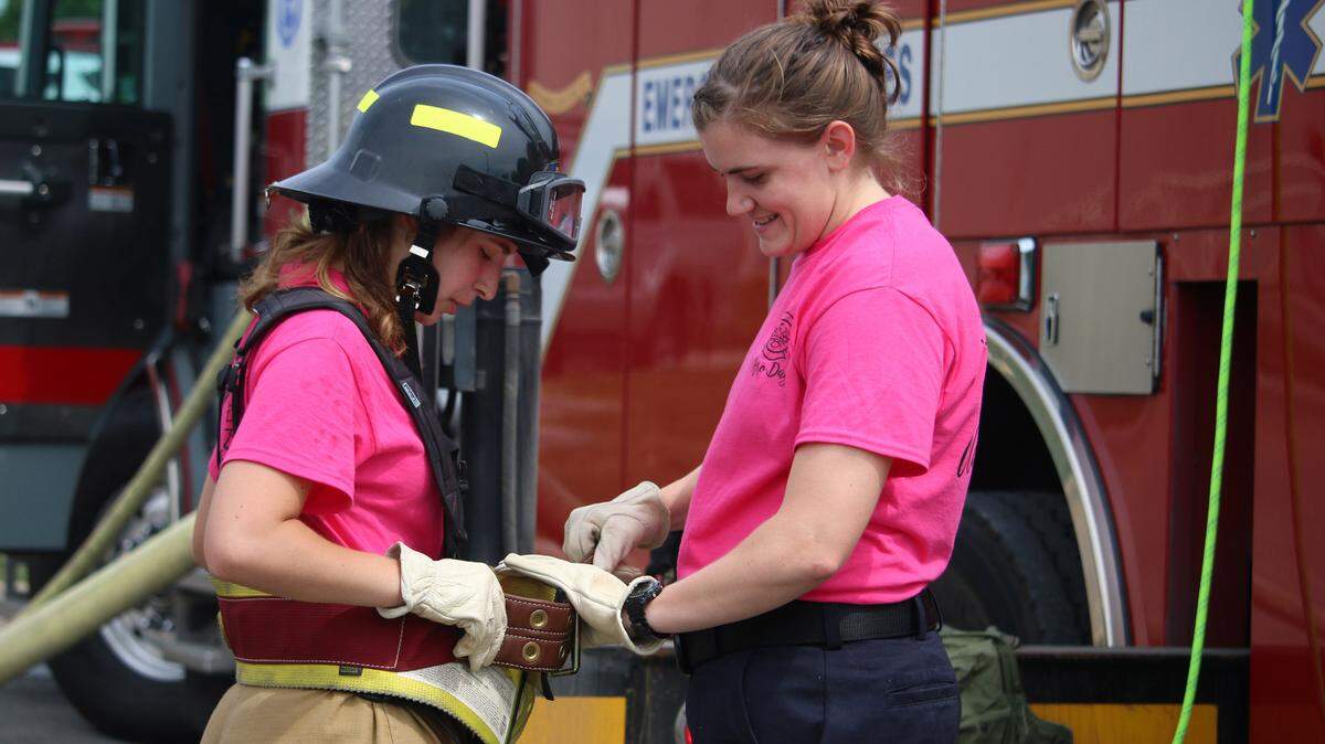 Olathe firefighter Emily Peterson, right, helps 18-year-old Sophie Simon adjust her equipment before climbing a 75-foot fire ladder called a quint. Simon is a German exchange student currently living in Baldwin City.