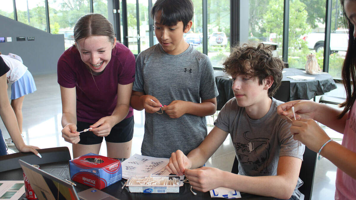 Vivian Nelson, 14, Wynn Stawarz, 12, and Ezra Purin, 15, watch a computer tutorial on how to make a Q-tip and rubber band bow and arrow.