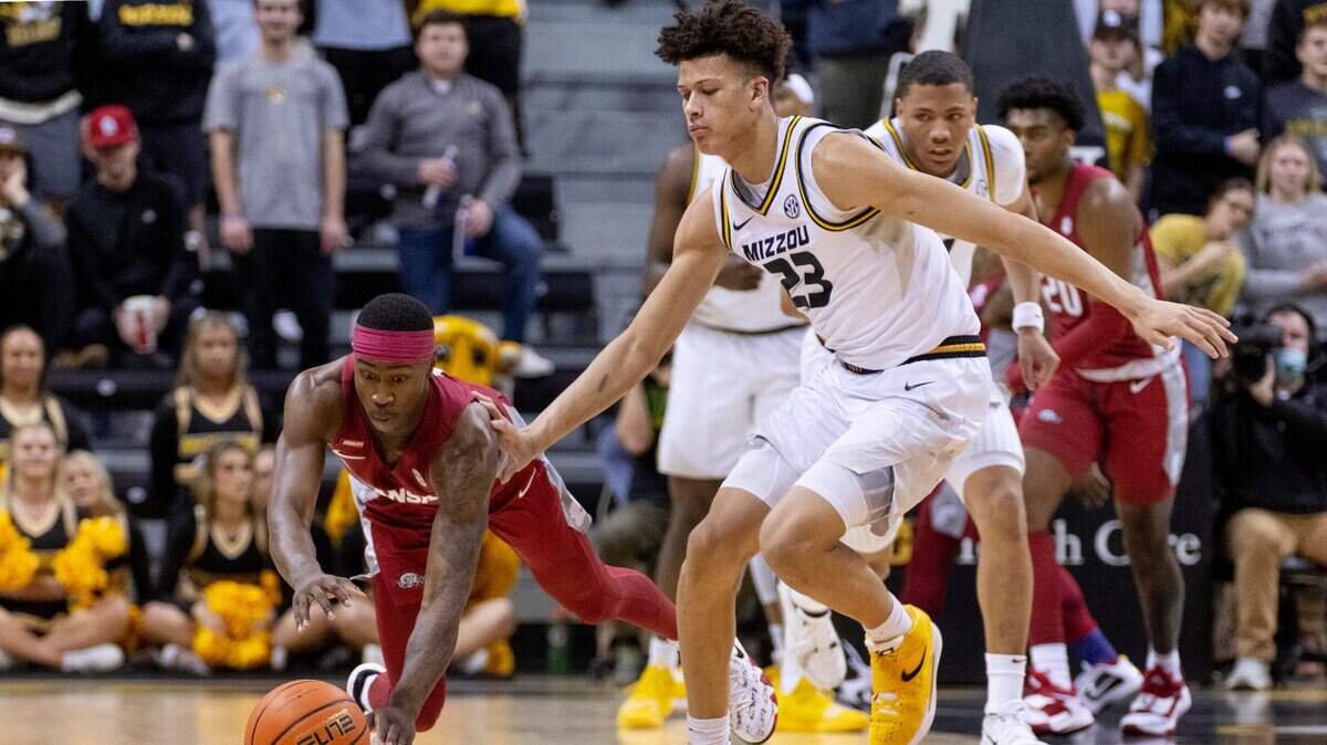 Arkansas’s Davonte Davis, left, dives for the ball in front of Missouri’s Trevon Brazile, right, during the first half of an NCAA college basketball game Tuesday, Feb. 15, 2022, in Columbia, Mo. (AP Photo/L.G. Patterson)