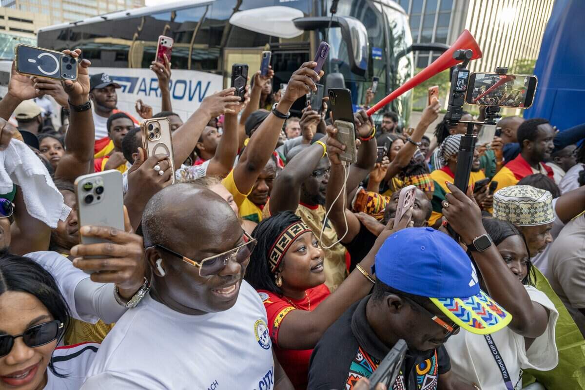 Ghana supporters hold up mobile phones as they stand behind barricades while the Ghana national team players get off the bus outside the Sheraton Kansas City Hotel on Wednesday, July 1, 2026.