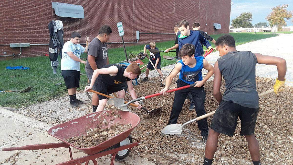 More than 25 members of the Pleasant Lea Middle School football team spent part of a warm weekend this fall pulling weeds at the Lee’s Summit school, installing a weed barrier and covering it with rocks.