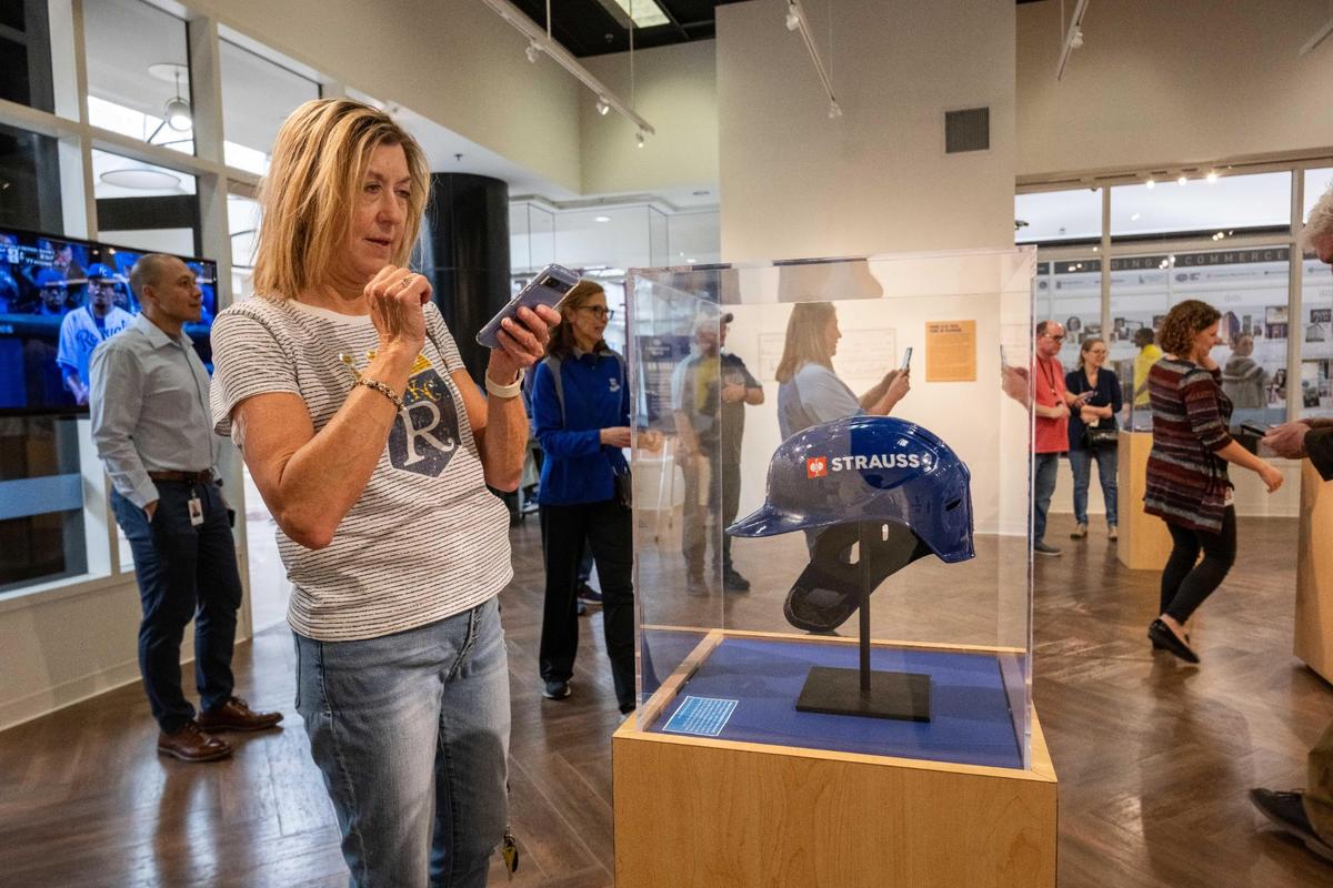 Rita Marks takes a photo of Royals first baseman Vinnie Pasquantino’s game worn helmet at the Royals’ Crowning Achievements Exhibit at Commerce Bank in downtown Kansas City.