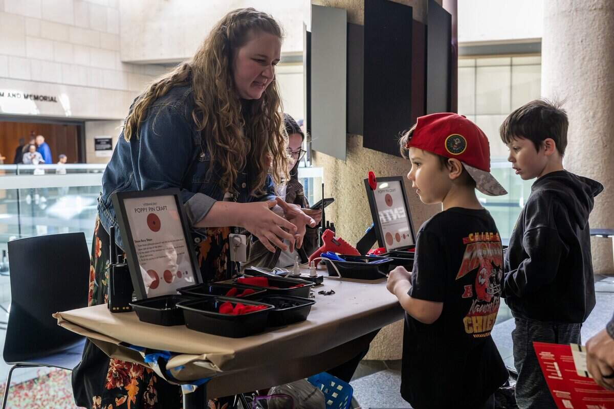 Madeline Thomas, education programs associate, explains how to make felt poppy pins to young visitors at the craft booth in honor of Veterans Day at the National WWI Museum and Memorial on Tuesday, Nov. 11, 2025.