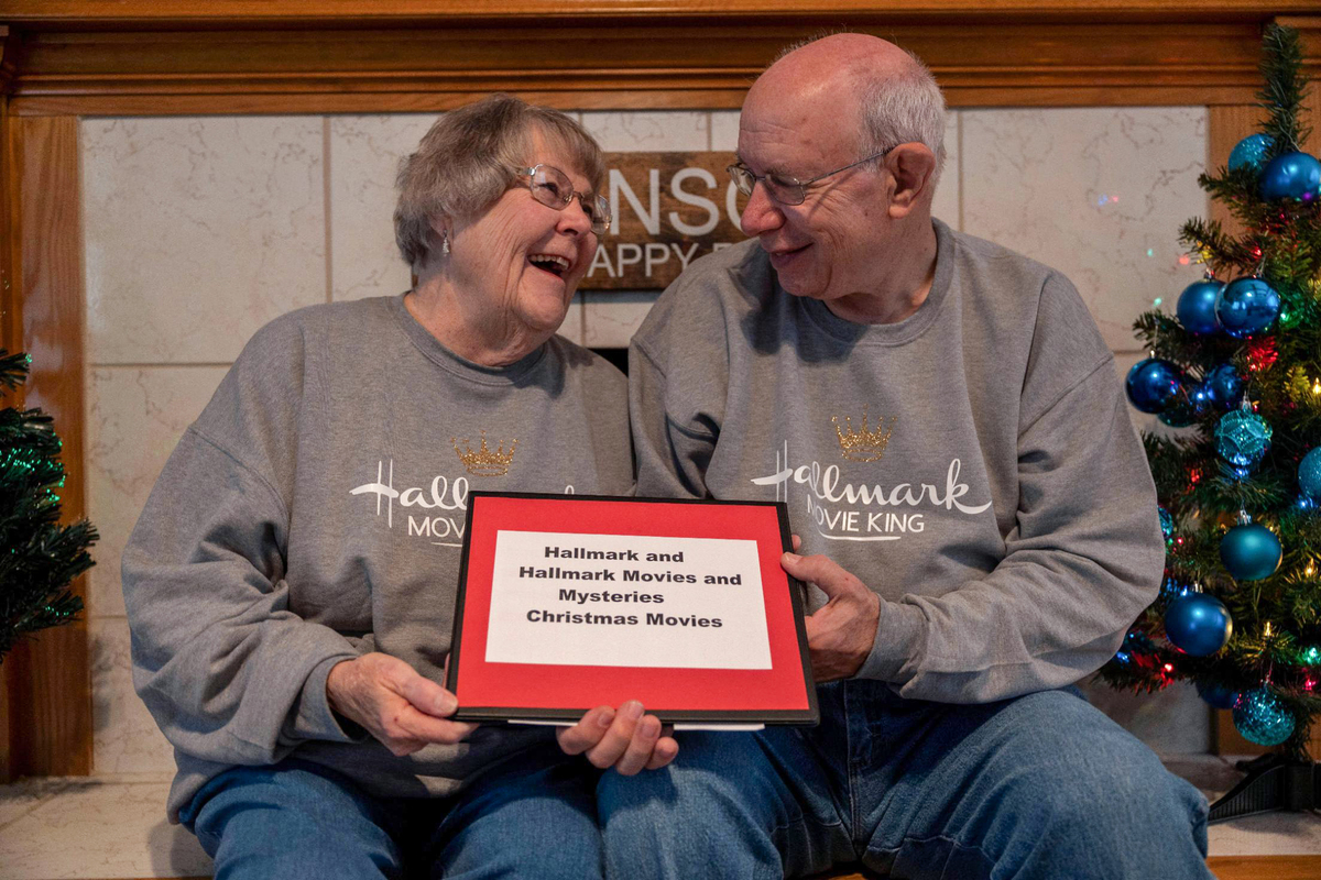 Cheryl and Joe Maggio hold their notebook documenting all the Hallmark and Lifetime movies they have watched since 2016.