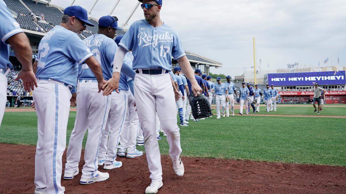 Kansas City Royals’ Hunter Dozier slaps hands with hitting coach Mike Tosar as they celebrate a win over the Tampa Bay Rays during a baseball game Sunday, July 24, 2022, in Kansas City, Mo. (AP Photo/Ed Zurga)