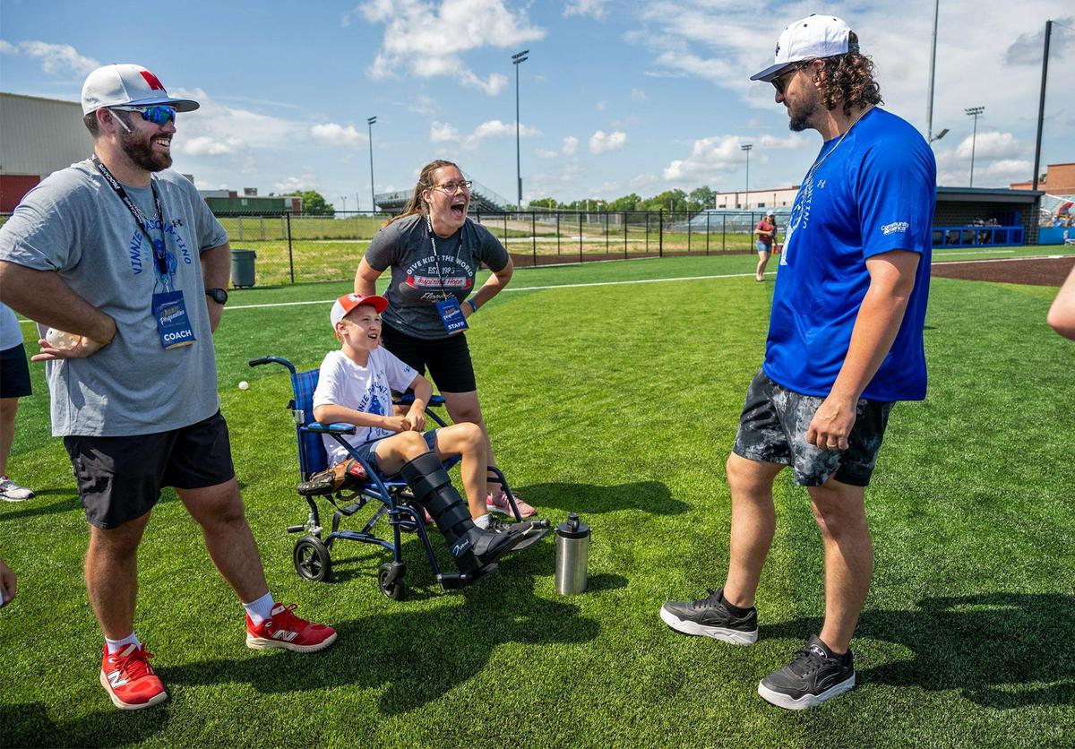 Nick Howard, left, a baseball coach from Bishop Miege High School, looks on Kansas City Royals first baseman Vinnie Pasquantino, right, talked with Noah Farrow, 13, and his mother, Kristi Farrow, of South Kansas City, during the Vinnie Pasquantino Baseball ProCamp at Grandview High School on Thursday in Grandview, Missouri. Noah, who broken his leg on Sunday, was still able to bat and participate in the camp.