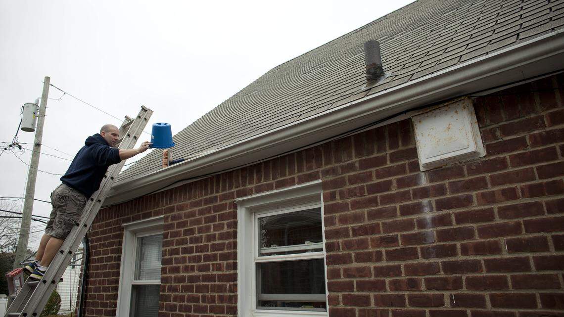 A man checks his roof and gutters.