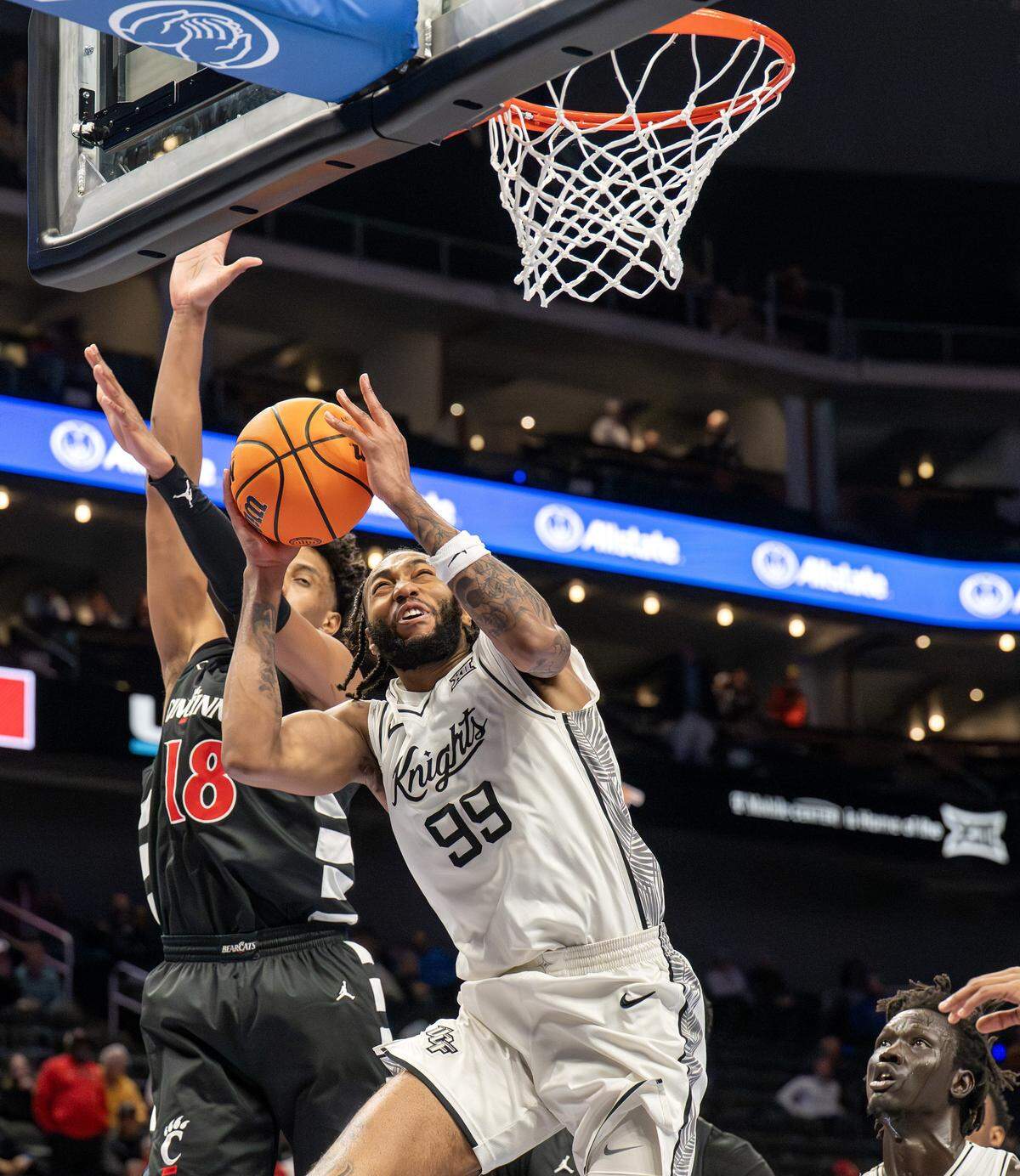 UCF Knights forward Jordan Burks (99) makes a layup over Cincinnati Bearcats forward Baba Miller (18) during the second half of a Big 12 Men's Basketball Tournament game at T-Mobile Center on Wednesday, March 11, 2026, in Kansas City.