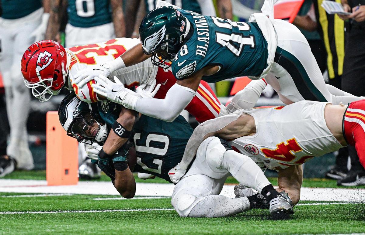 Philadelphia Eagles running back Saquon Barkley (26) is tackled by Kansas City Chiefs cornerback Jaylen Watson (35) and linebacker Leo Chenal (54) in the third quarter during Super Bowl LIX on Sunday, Feb. 9, 2025, in New Orleans.