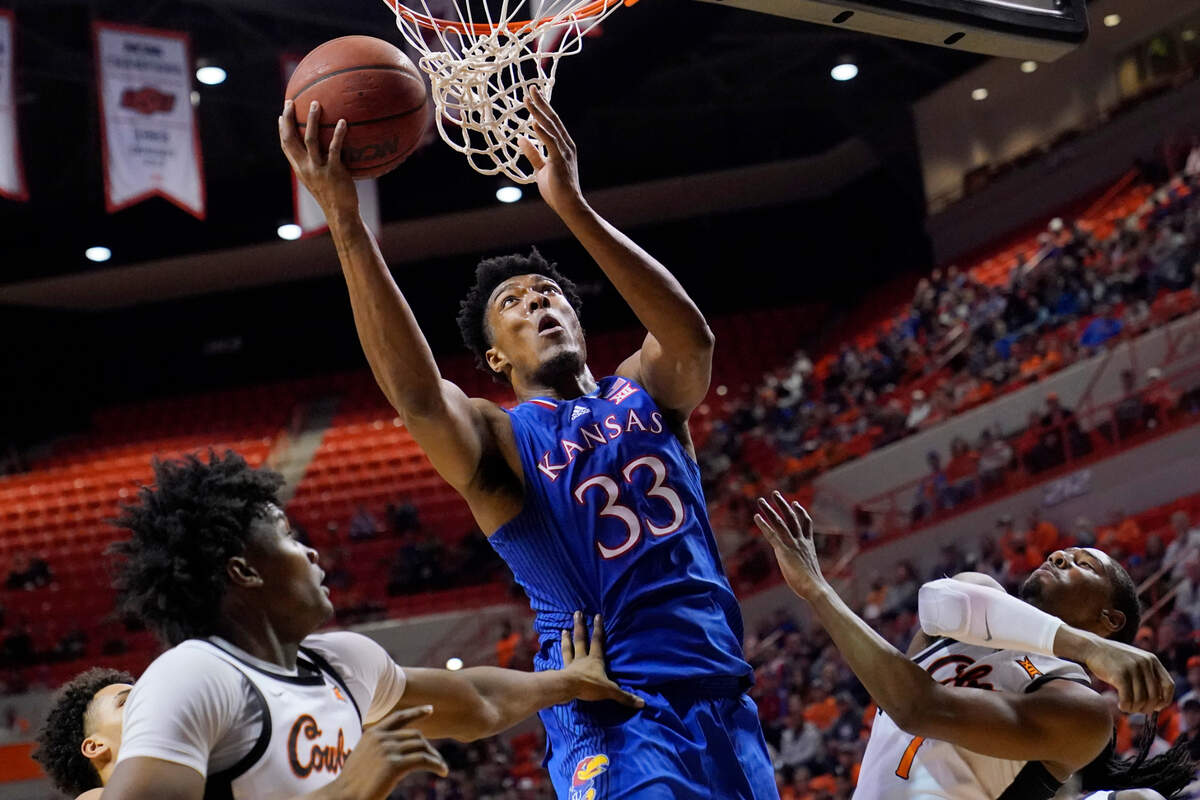 Kansas forward David McCormack (33) shoots between Oklahoma State forward Matthew-Alexander Moncrieffe, left, and guard Bryce Thompson, right, in the first half of an NCAA college basketball game Tuesday, Jan. 4, 2022, in Stillwater, Okla. (AP Photo/Sue Ogrocki)
