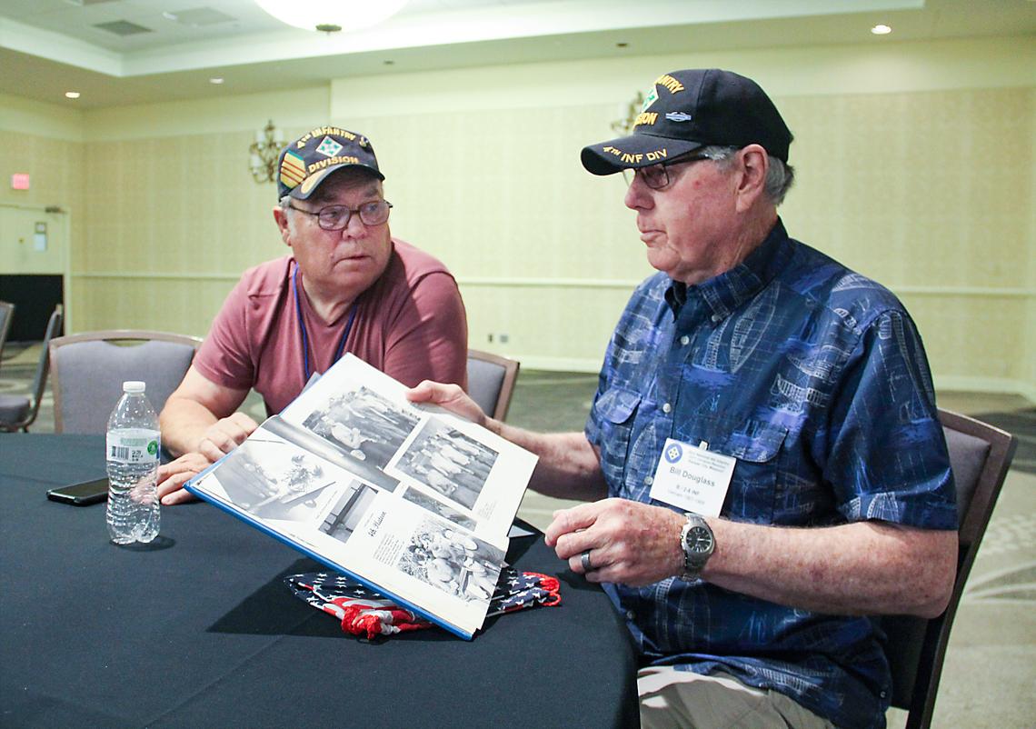 Bill Douglass, right, flips through a Vietnam photo album as Charles Neidel looks on.
