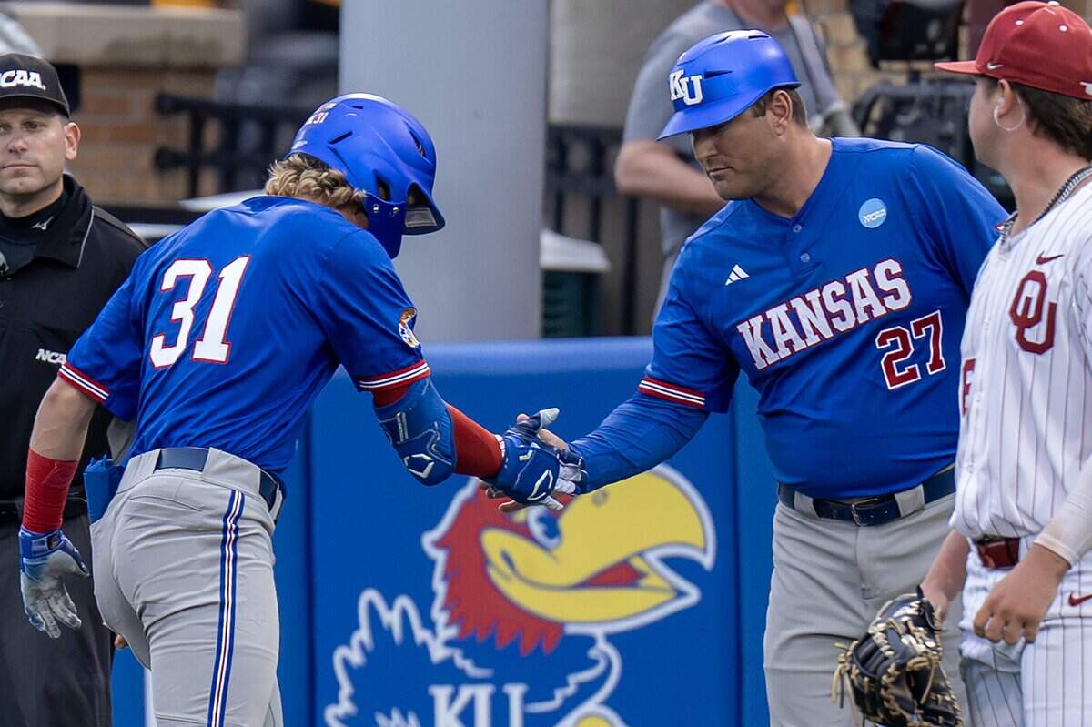 Kansas utility player Jordan Bach (31) celebrates with assistant coach Jon Coyne after hitting an RBI single during an NCAA Super Regional baseball game against Oklahoma at Hoglund Ballpark on Sunday, June 7, 2026, in Lawrence.
