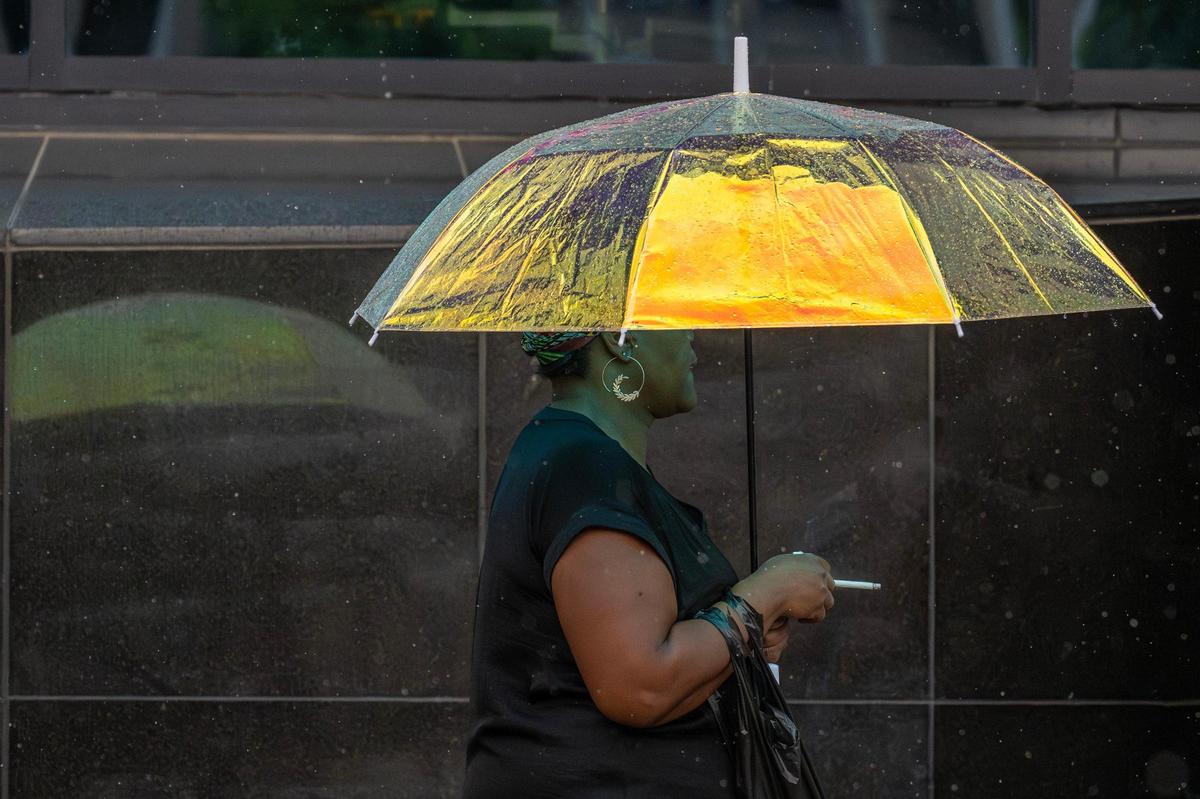 A commuter makes their way down Main Street under an umbrella in the rain on Tuesday, June 3, 2025, in Kansas City.