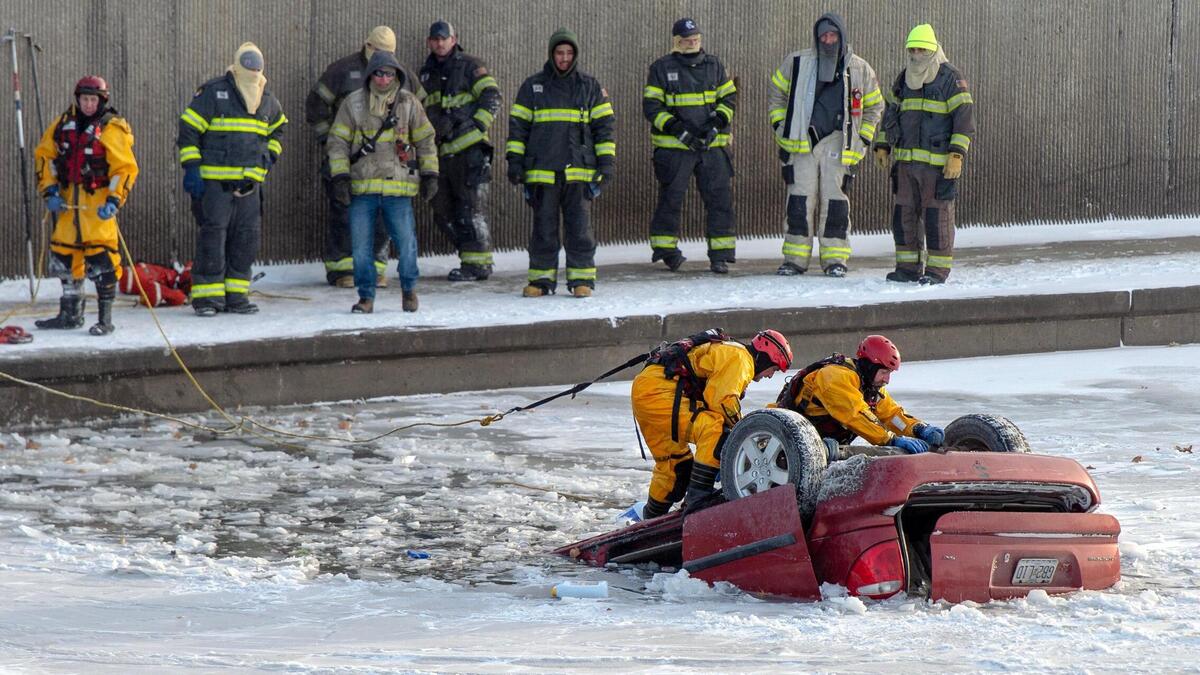 Kansas City firefighters attach tow straps to a vehicle in Brush Creek on Thursday, Dec. 22, 2022, in Kansas City.