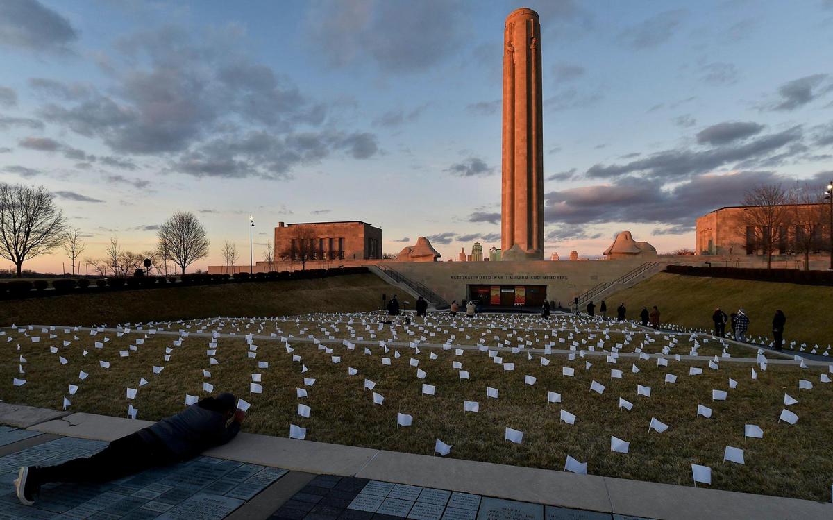 People who lost their lives to COVID-19 were remembered and frontline workers were honored on the National Day of Remembrance Tuesday, Jan. 19, 2021. A white flag for each of the 1,665 people who died of COVID in the Kansas City metro area was planted in front of the National World War I Museum and Memorial and the city skyline was lit in amber. This coincided with ceremonies across the country. A visitor takes a low-angle shot of the display.