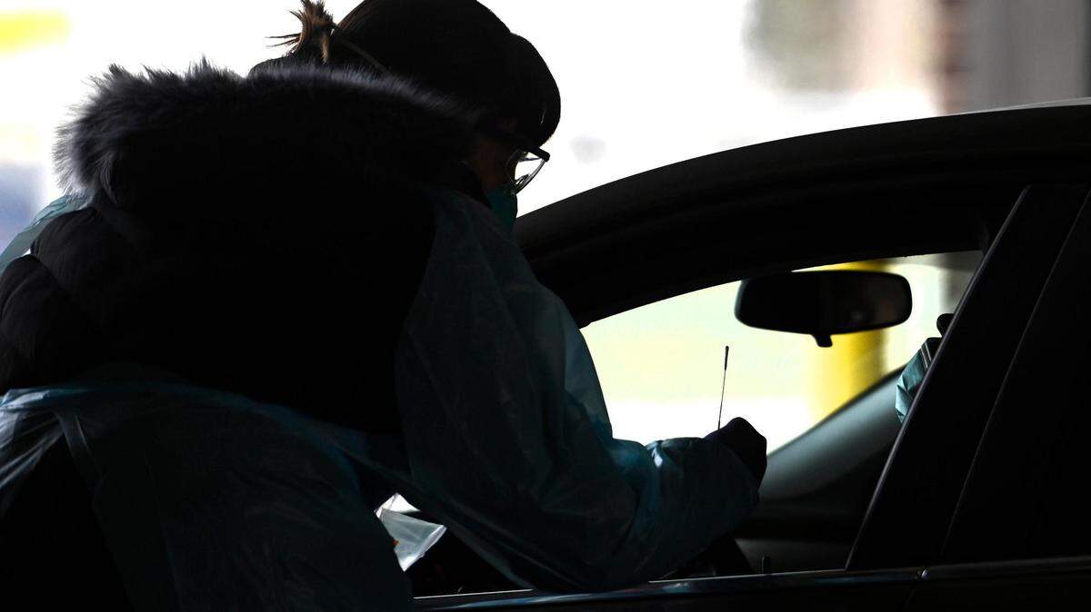 A registered nurse prepares to take a nasal swab during a drive-thru COVID-19 testing site. Kansas is moving closer to viewing COVID-19 as an endemic disease.