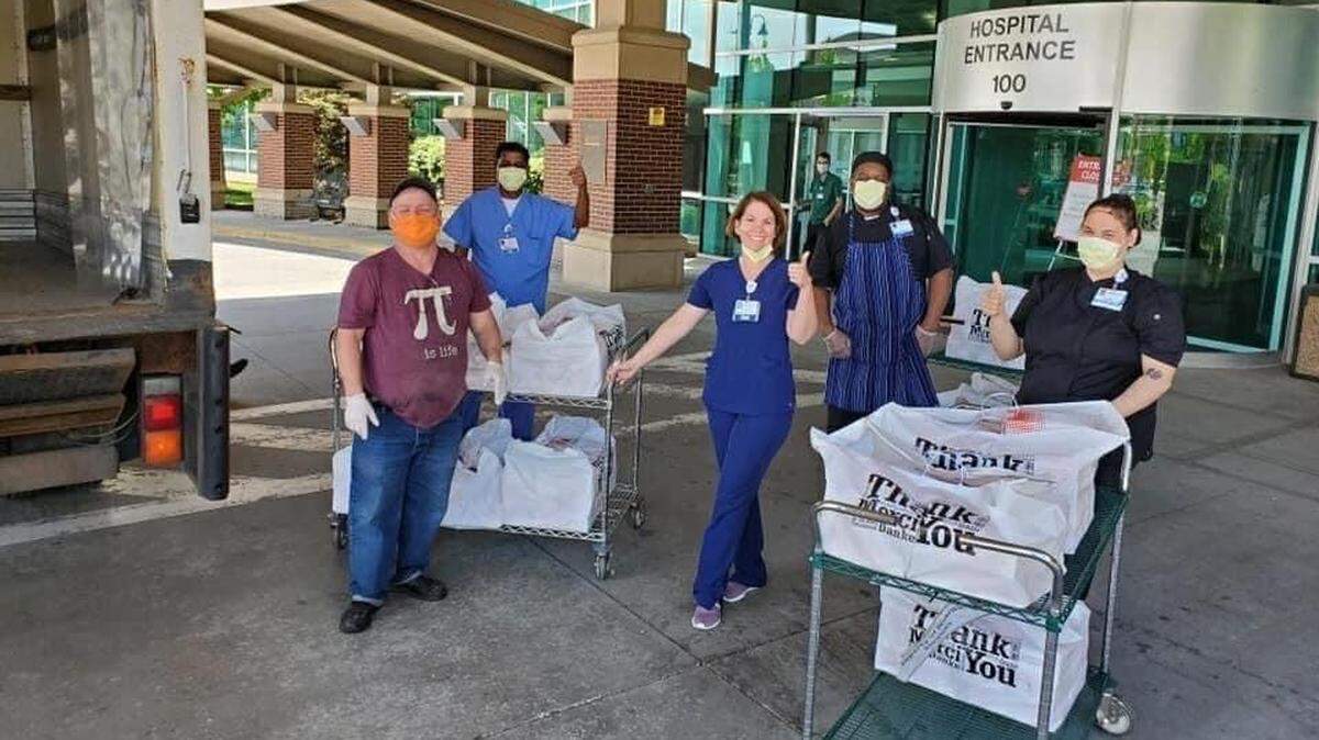 Workers at Saint Luke’s East Hospital accept a delivery of meals from the Neighborhood Cafe in Lee’s Summit.