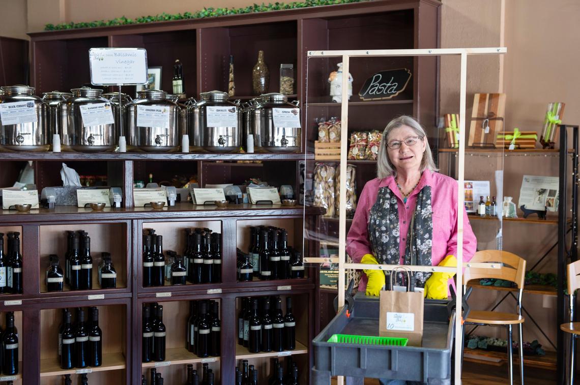 Jeanne Mackay and her husband, Jay, operate the Tasteful Olive in downtown Overland Park. They are selling olive oil and other products through phone and online orders. Jeanne uses a cart with a shield Jay added so they can meet customers at the front door of the store with their orders.