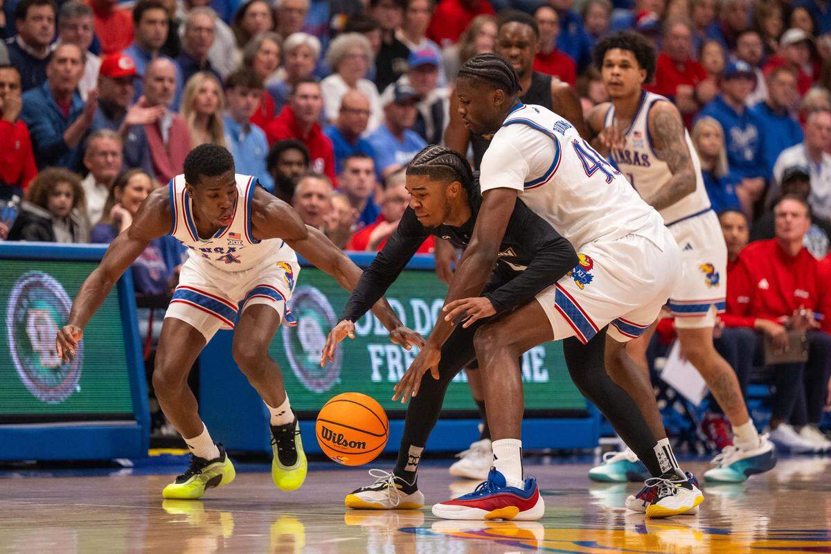 Kansas Jayhawks guard Melvin Council Jr. and forward Flory Bidunga (40) defend a Towson Tigers player in the first half on Tuesday, December 16, 2025, at Allen Fieldhouse.