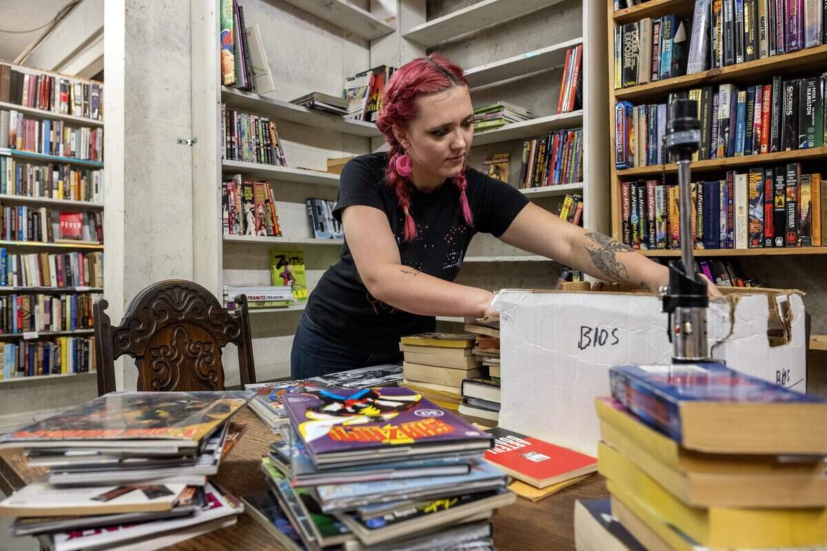 Adriana Stewart, an employee at Steel's Used Books, unpacks boxes of books and places them on shelves at the shop on Tuesday, June 23, 2026, in Kansas City.
