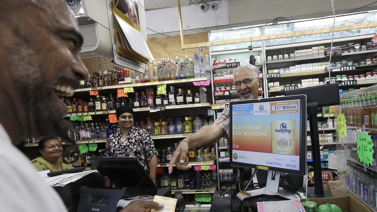 Mike Bostic, left, smiles as he is handed a lottery ticket by owner Kewal Sachdev at Ernie’s Liquors in San Jose, Calif., Wednesday, July 25, 2018.