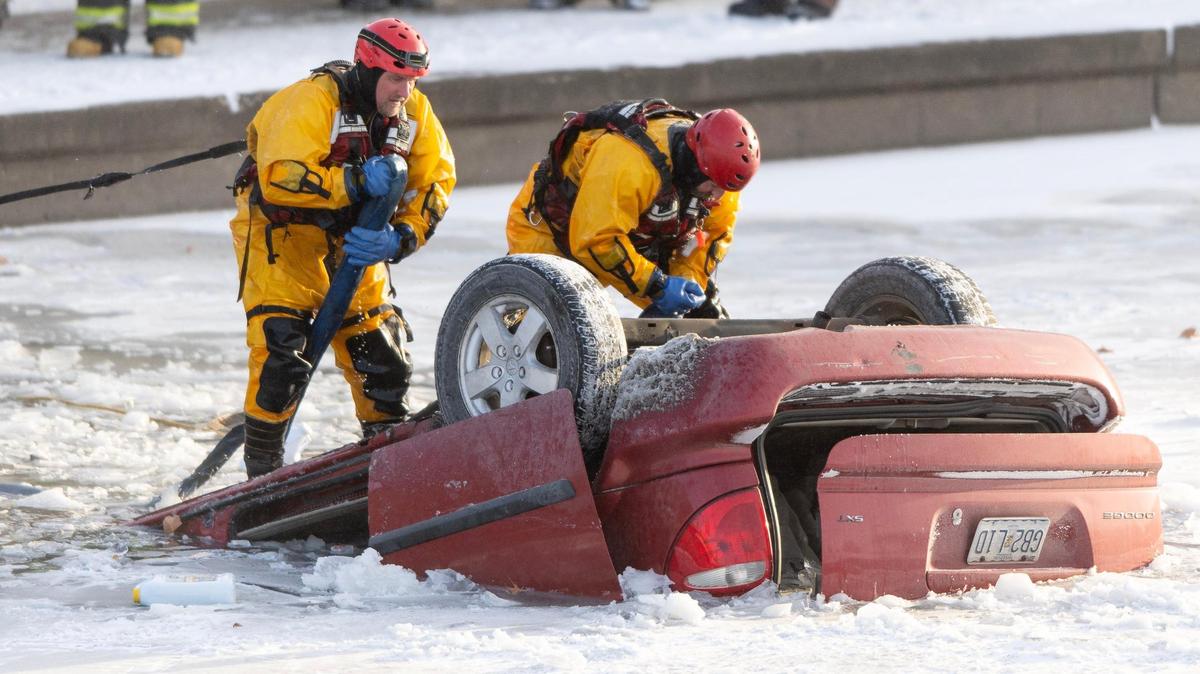 Kansas City firefighters attach tow straps to a vehicle in Brush Creek on Thursday, Dec. 22, 2022, in Kansas City.