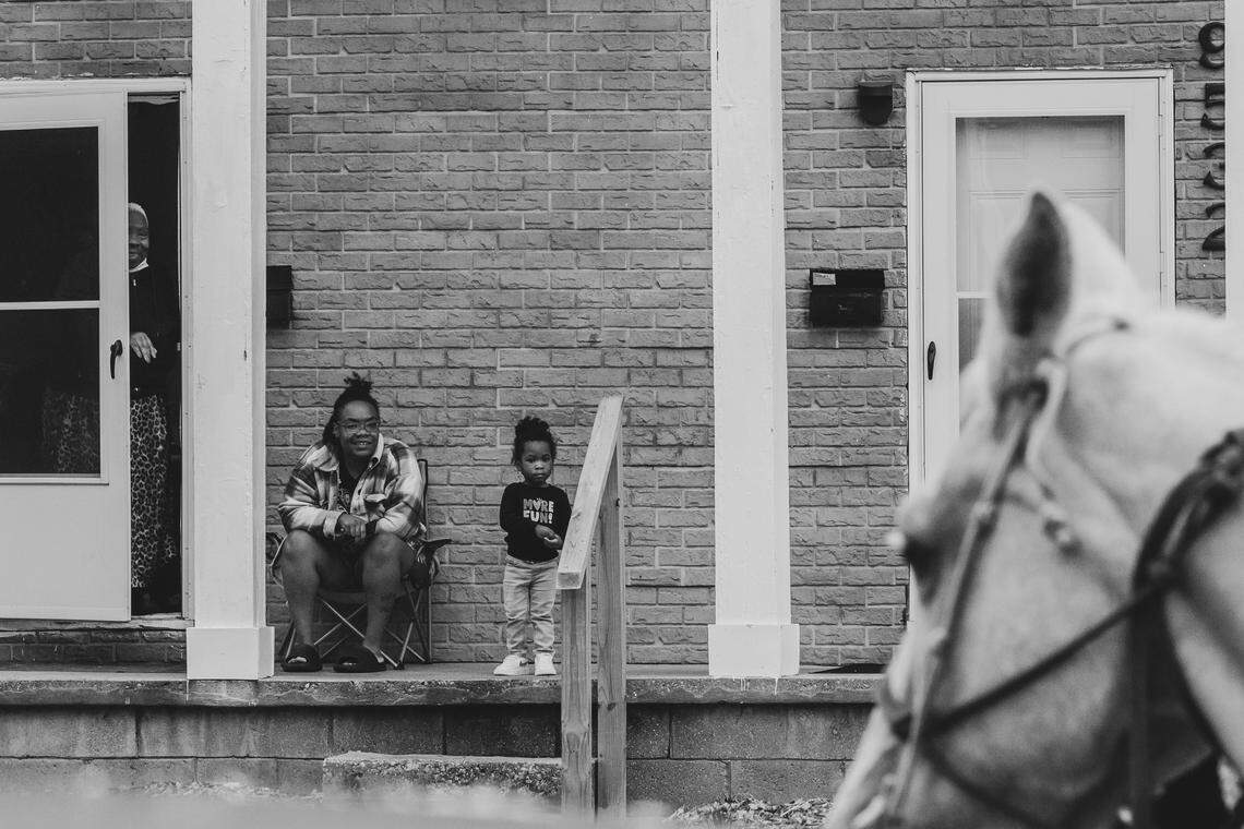 A mother and daughter watch as Your’Majesty El Bey rides his horse ‘Goldie’ up to their door during a community outreach ride with KCPD in Kansas City. The horses encourage people to come outside, let their guard down, and interact in a more positive way towards the police.