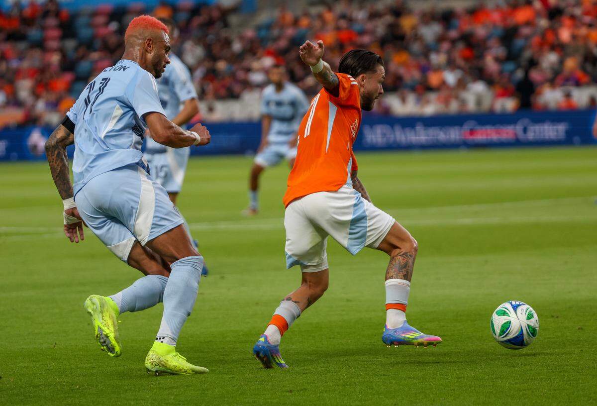 Dynamo midfielder Sebastian Kowalczyk, right, dribbles away from Sporting Kansas City forward Khiry Shelton during a Major League Soccer match at Shell Energy Stadium in Houston on Saturday, May 31, 2025.