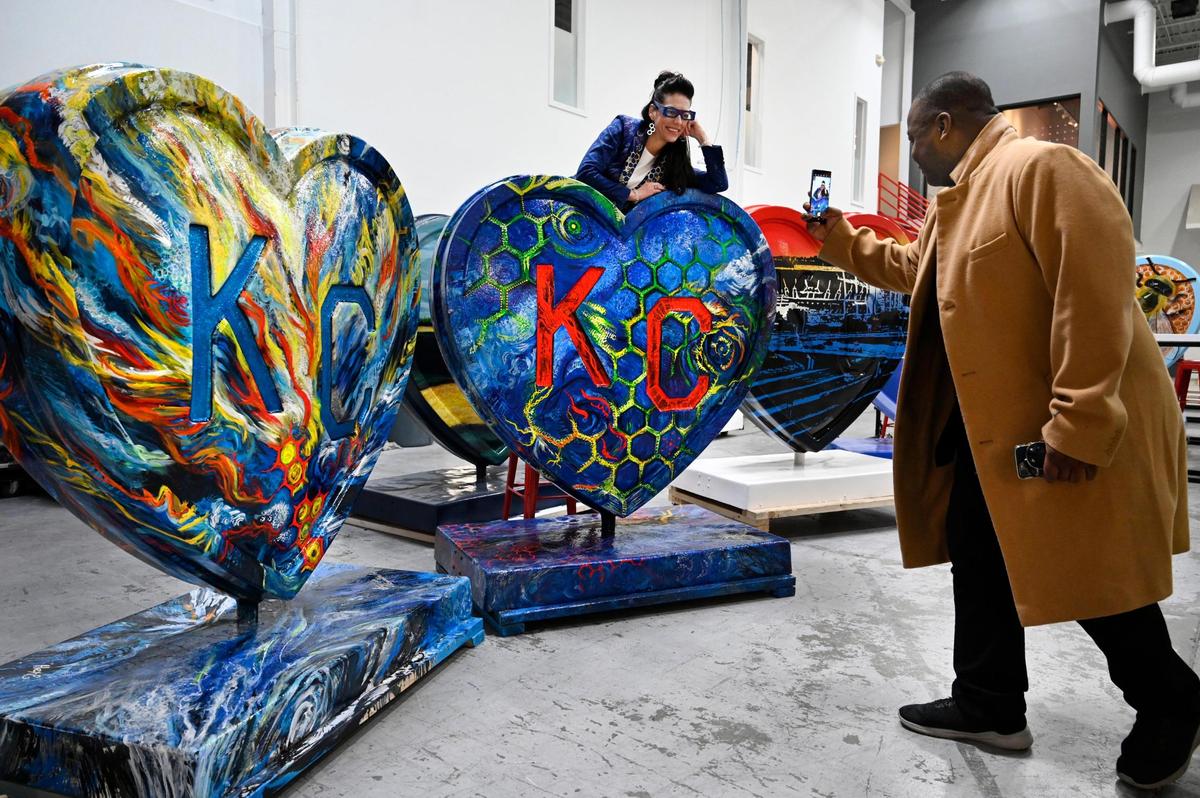 Artist Eugenia Ortiz, left, posed for a photo as friend Anthony Burnside snapped a few photos with the two oversized hearts Ortiz created for the upcoming Parade of Hearts. Ortiz was one of three artists on hand at Dimensional Innovations on Monday, Feb. 14, 2022 in Overland Park during a preview for the for the Parade of Hearts, an event that will display over 150 hearts created by local artists throughout the Kansas City area. The hearts will go on public display in mid-March. Originally from Los Angeles, Ortiz, who created two hearts, is a traveling artist now based in Kansas City. The hearts will be auctioned off as a fundraiser for four charities that have been impacted by COVID-19.