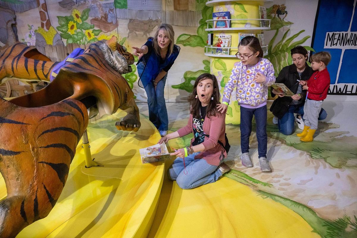 Volunteer Christina Fielder, from left, and visitors Maggie Vallette and her daughter, Mabel Vallette, 8, of Prairie Village, visit the exhibit “Sam and the Tigers” at The Rabbit hOle. Kylee Soucie of Kansas City, far right, reads to her son, Leo Soucie, 4, while waiting to explore the exhibit.