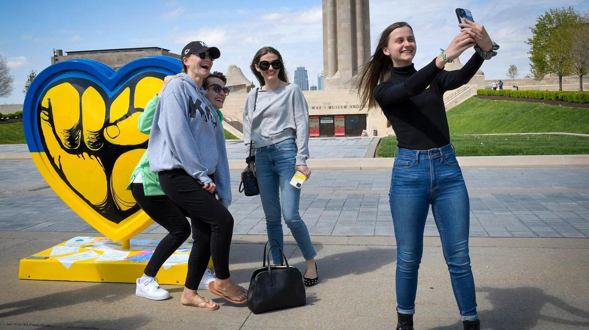 Marina Clark, of Blue Springs, from left, Yulia Petrenko, of Tacoma, Washington, and Anastasiia Novosad, of Olathe, pose for a photo taken by Mariya Slipych, of Olathe, after the Parade of Hearts unveiled “We Are With You,” a heart in support of the Ukrainian people, which was unveiled Thursday. The women, who now live in the United States, came out to show support for Ukraine, their homeland.