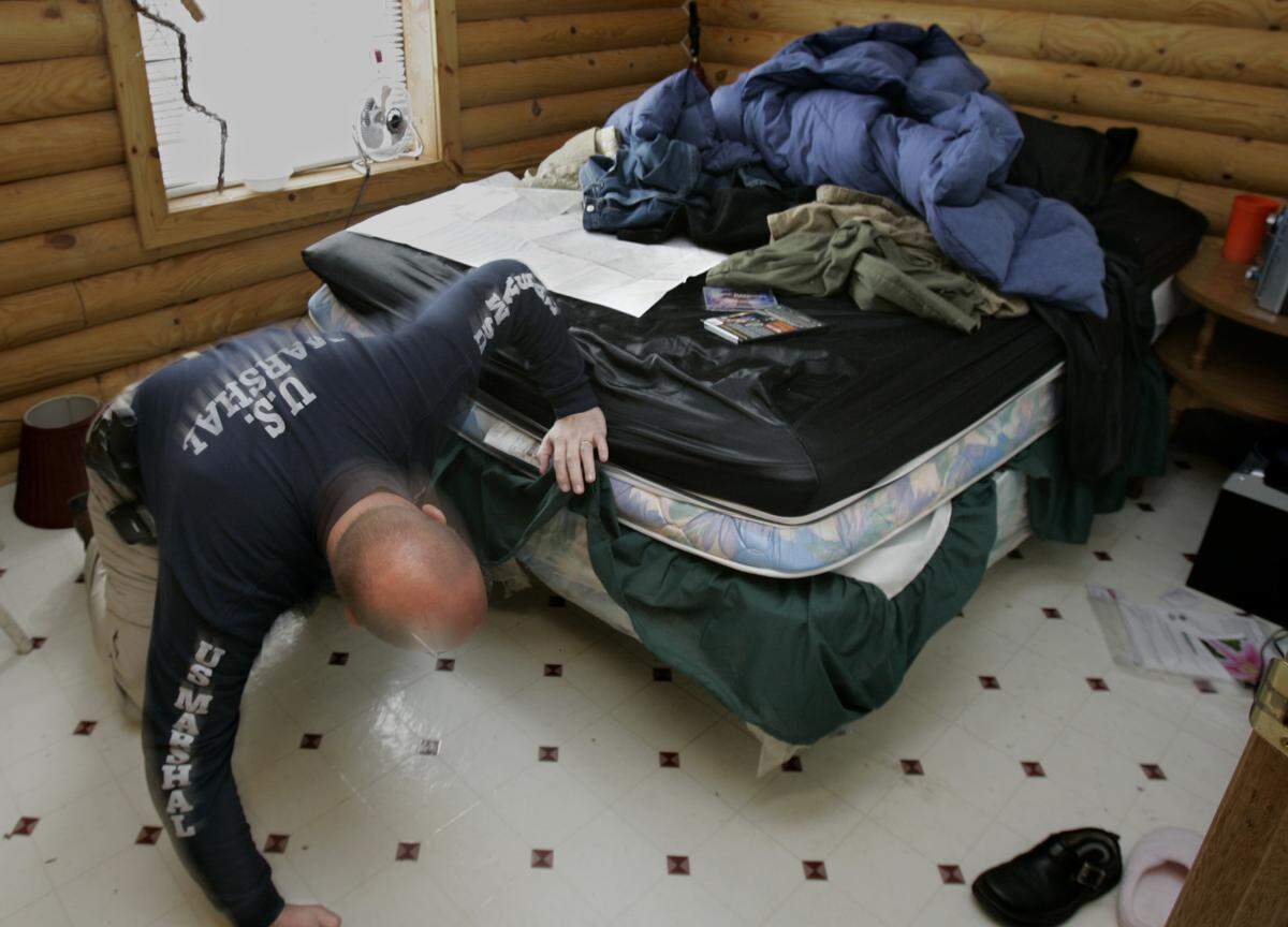 PHOTO BY: ALLISON LONG/KANSAS CITY STAR 022606 United States Marshal Chief Deputy Anthony Crawford looks under the main bedroom in the cabin in Alpine , Tenn., were Toby Young and John Manard stayed for 12 days after Young helped Manard escape from prison in Lansing, Kan. He was looking for items that may have moved during the initial search of the premises. cutline: U.S. Marshal Chief Deputy Tony Crawford looked Sunday in the main bedroom of the cabin in Alpine, Tenn., where Toby Young and John Manard stayed for 12 days. Efforts to extradite the couple back to Kansas begin today.