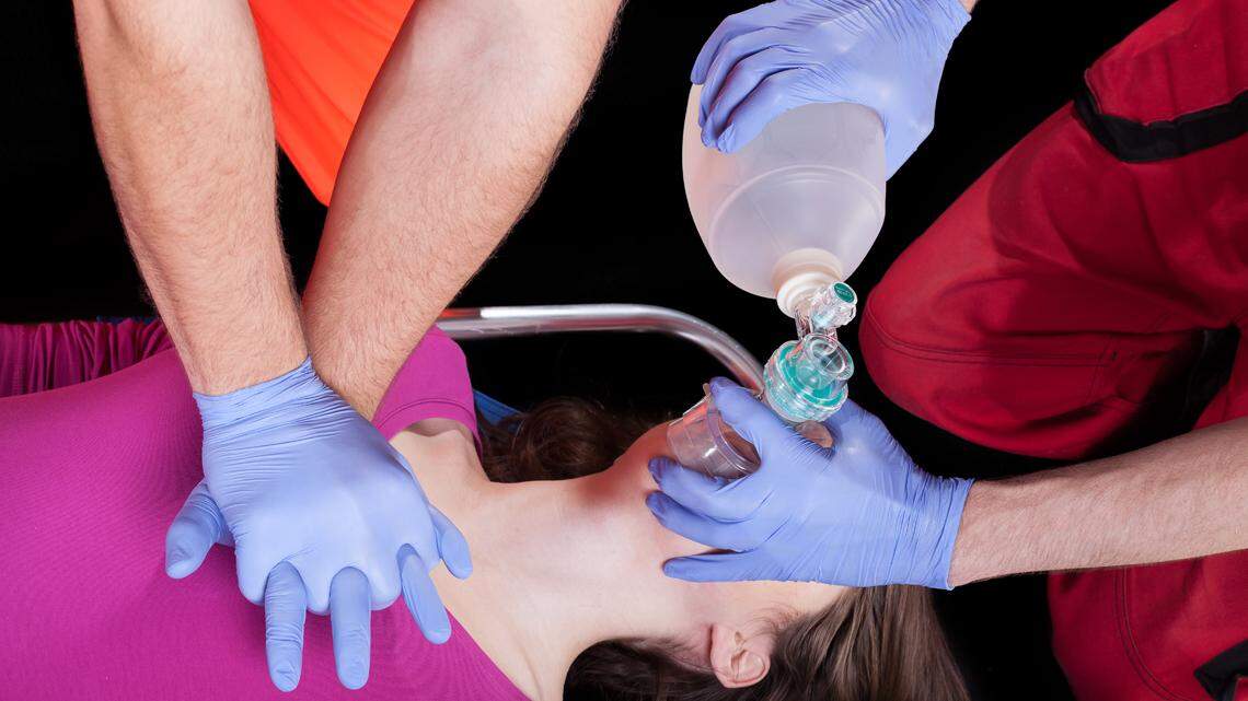 Two paramedics doing a heart massage and providing casualty with oxygen