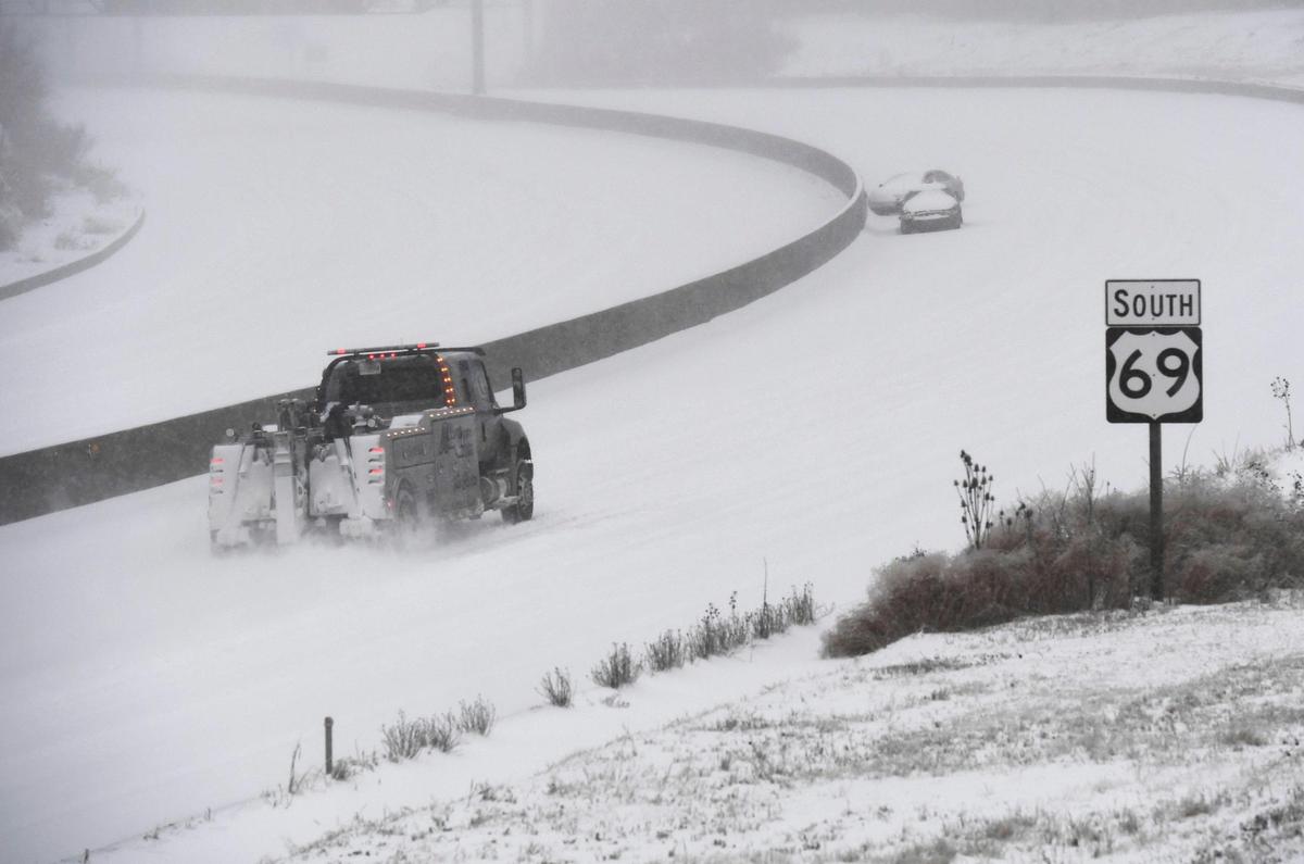 Vehicles sit stranded along southbound U.S. Highway 69 as a tow truck drives by Sunday, Jan. 5, 2025, in Overland Park.