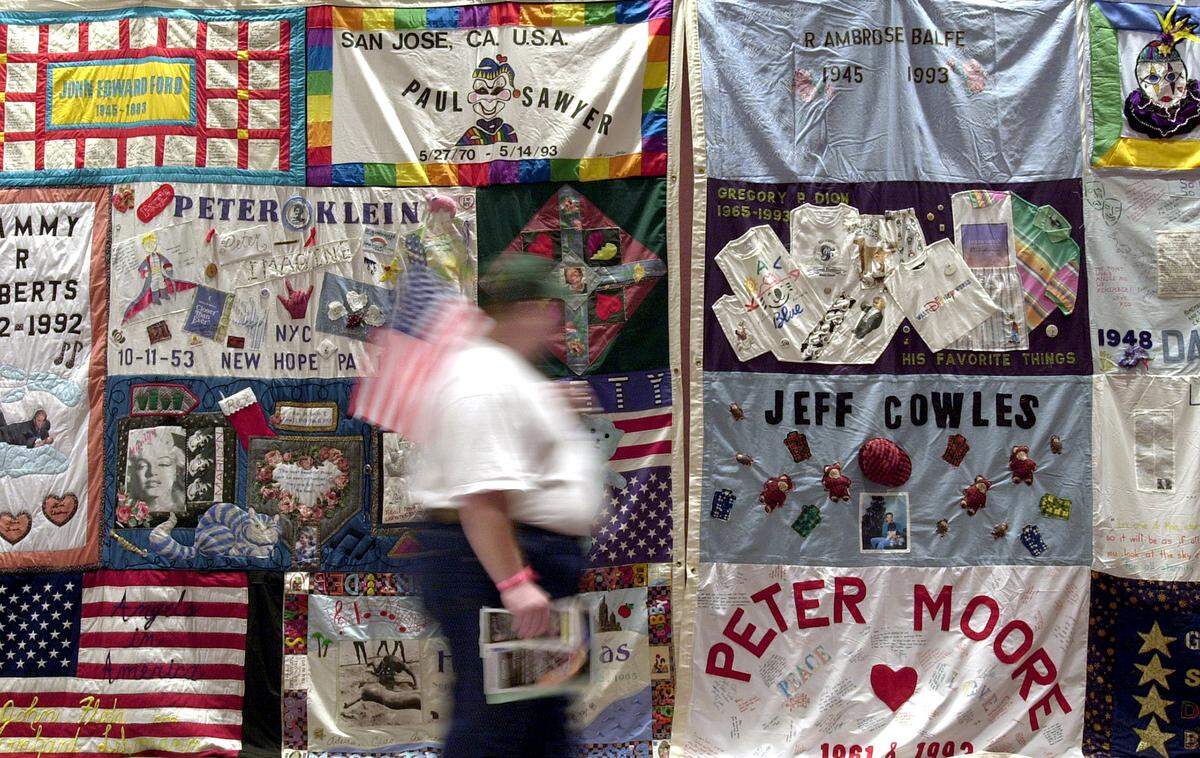 About 300 panels of the AIDS Memorial Quilt were displayed at Bartle Hall during the Gay and Lesbian Pride Festival in 2000. Carrying an American flag, Mark Owings of Kansas City passed by the quilt display.