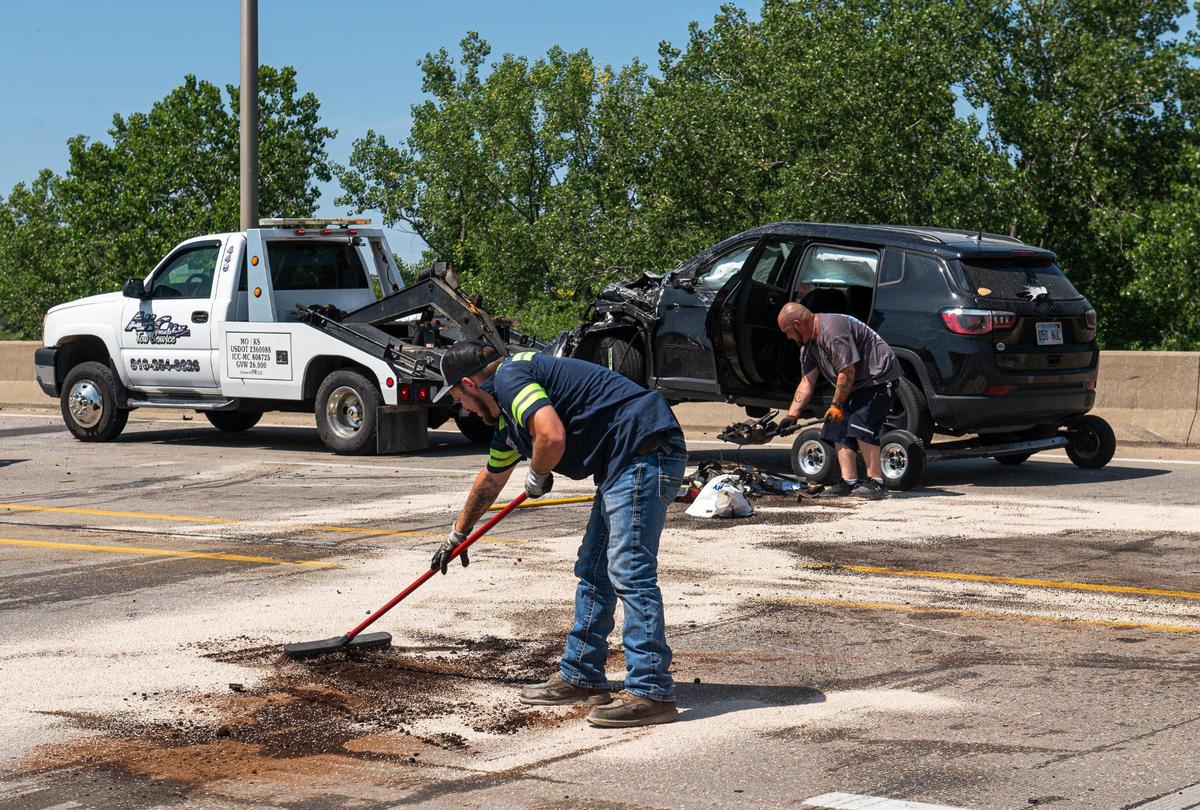 Clean up workers remove debris from the Seven Street Trafficway Bridge after a car wreck left one dead and two injured on Monday, June 19, 2023, in Kansas City, Kansas.