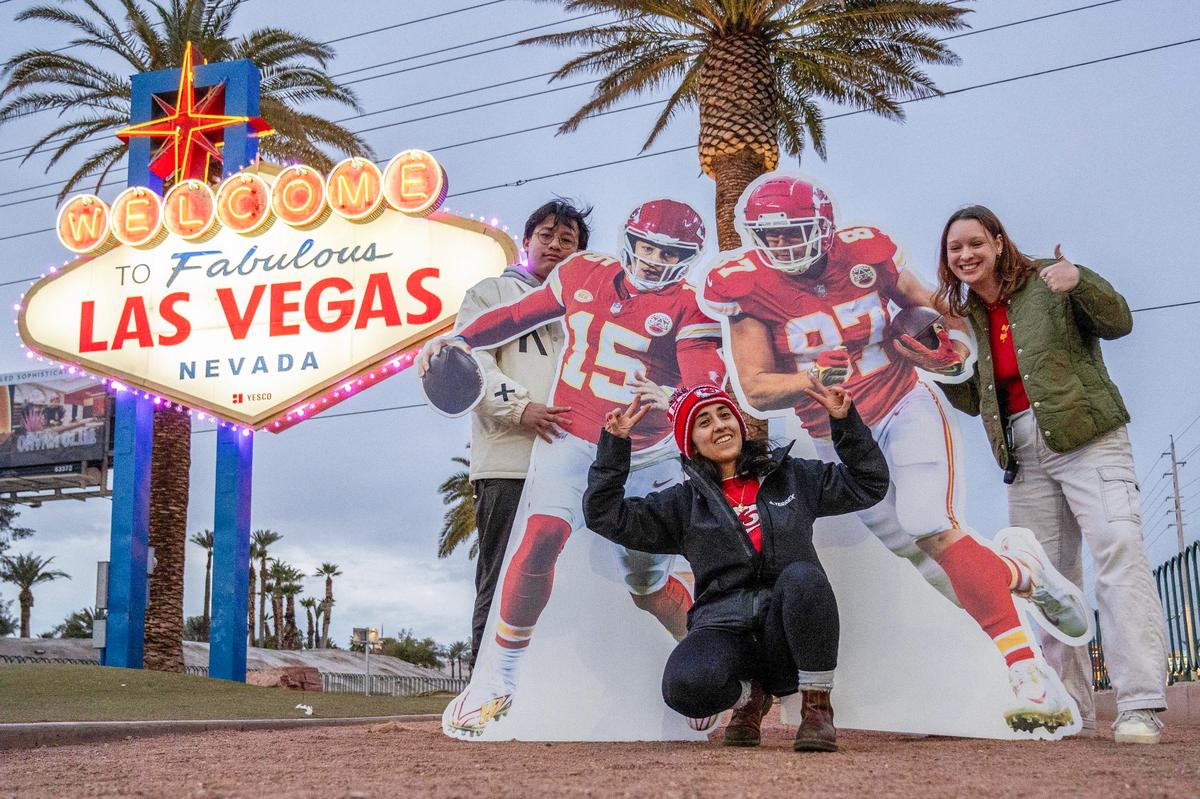 Kansas City Star journalists Irvin Zhang, left, Emily Curiel and Alison Booth pose for a photo in front of the Las Vegas welcome sign alongside life-size cutouts featuring Kansas City Chiefs quarterback Patrick Mahomes and tight end Travis Kelce.