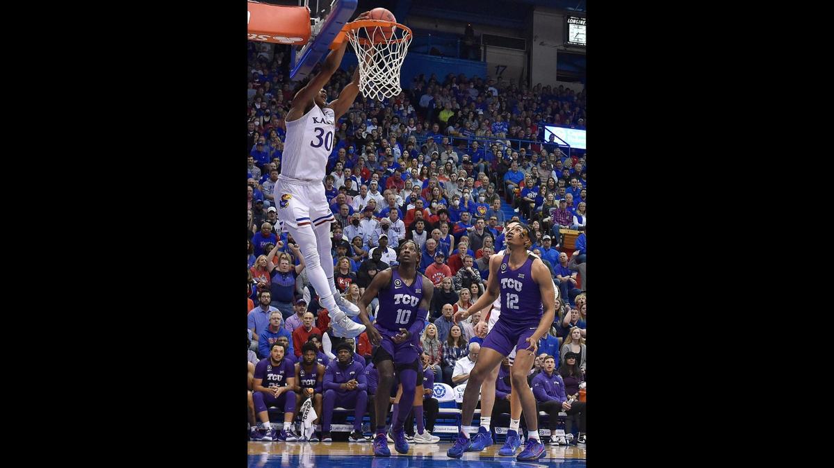 KU’s Ochai Agbaji got behind TCU’s Damion Baugh and Xavier Cork to slam home an alley-oop dunk during the first half of Thursday night’s Big 12 Conference game at Allen Fieldhouse.