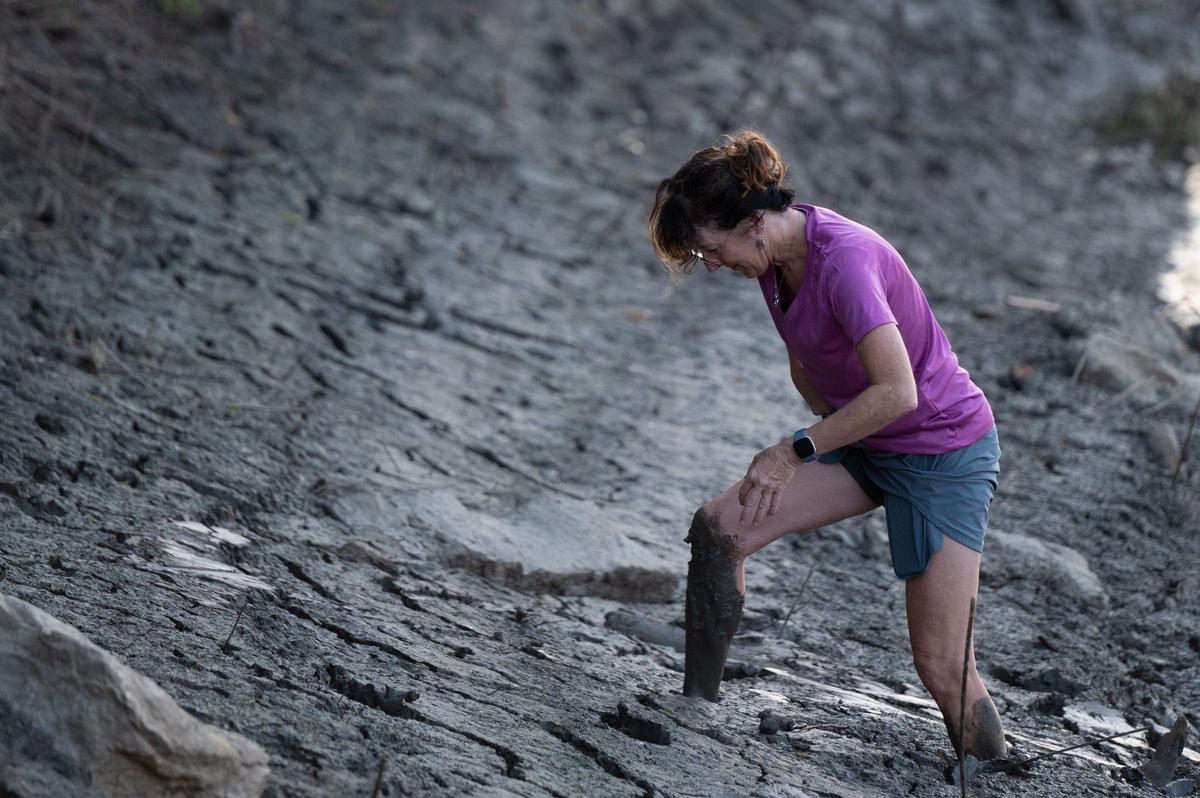 Cindy Falterman hikes out of knee deep mud on the shore of the Missouri River after helping push off son David in the MR340 river race.