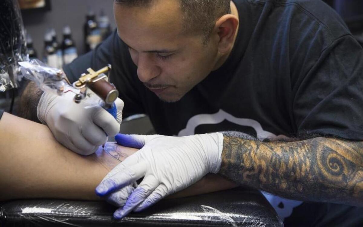 Tattoo artist Julio Morales adds color to the sleeve of client Ricardo Gallardo of St. Louis, who waited more than a year for his appointment.