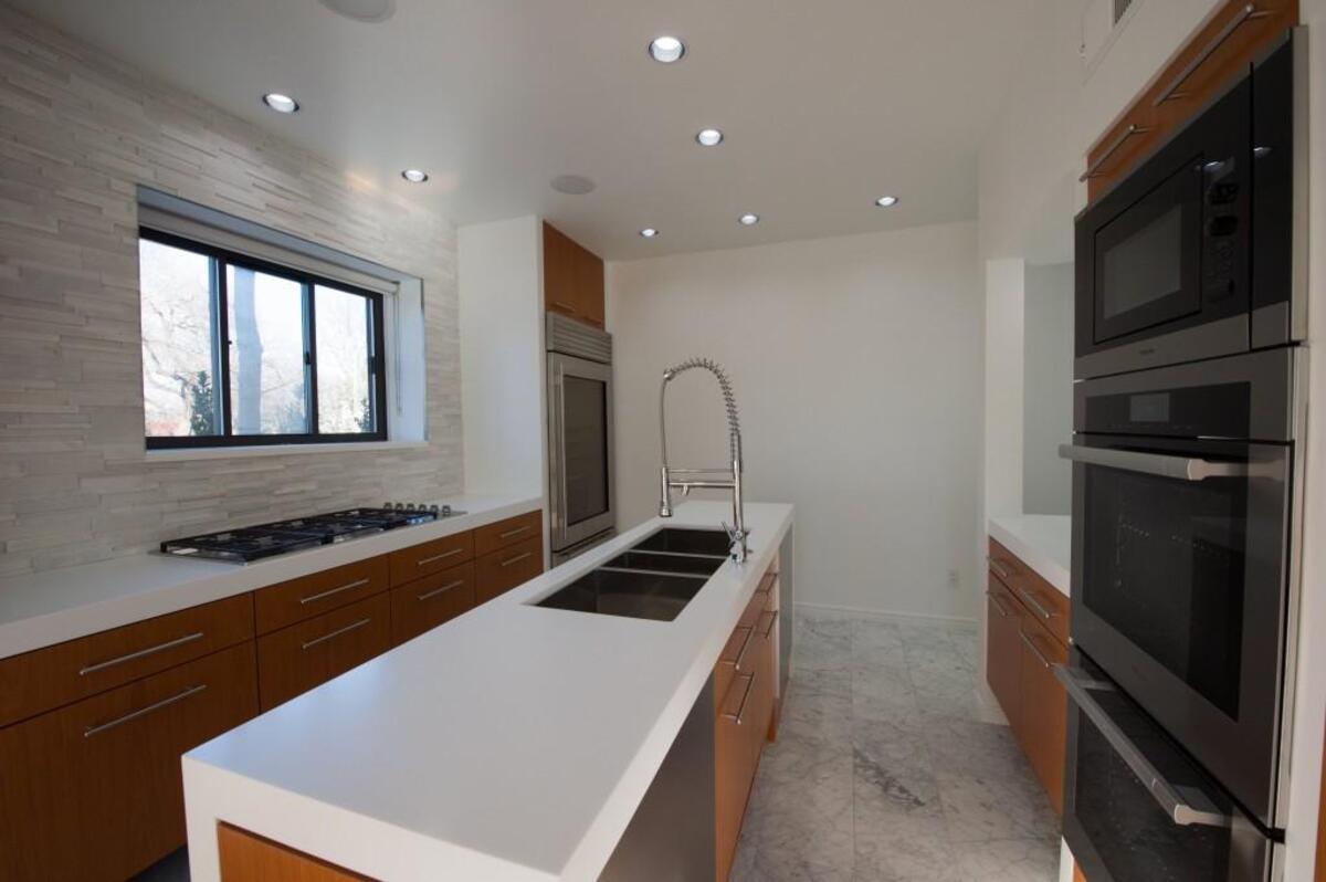 The brand new kitchen has Miele and Subzero appliances, white Corian counters and a textured Carrera marble tile backsplash. There are no upper cabinets.