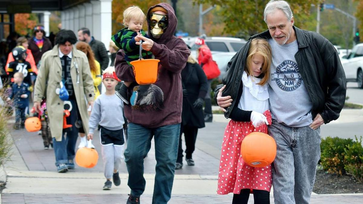 Shannon Enslow, from Prairie Village, Kansas, kept warm under the jacket of Doug Royen, of Overland Park during a Halloween Trick or Treating event at Prairie Village Shopping Center in 2017 in Prairie Village.
